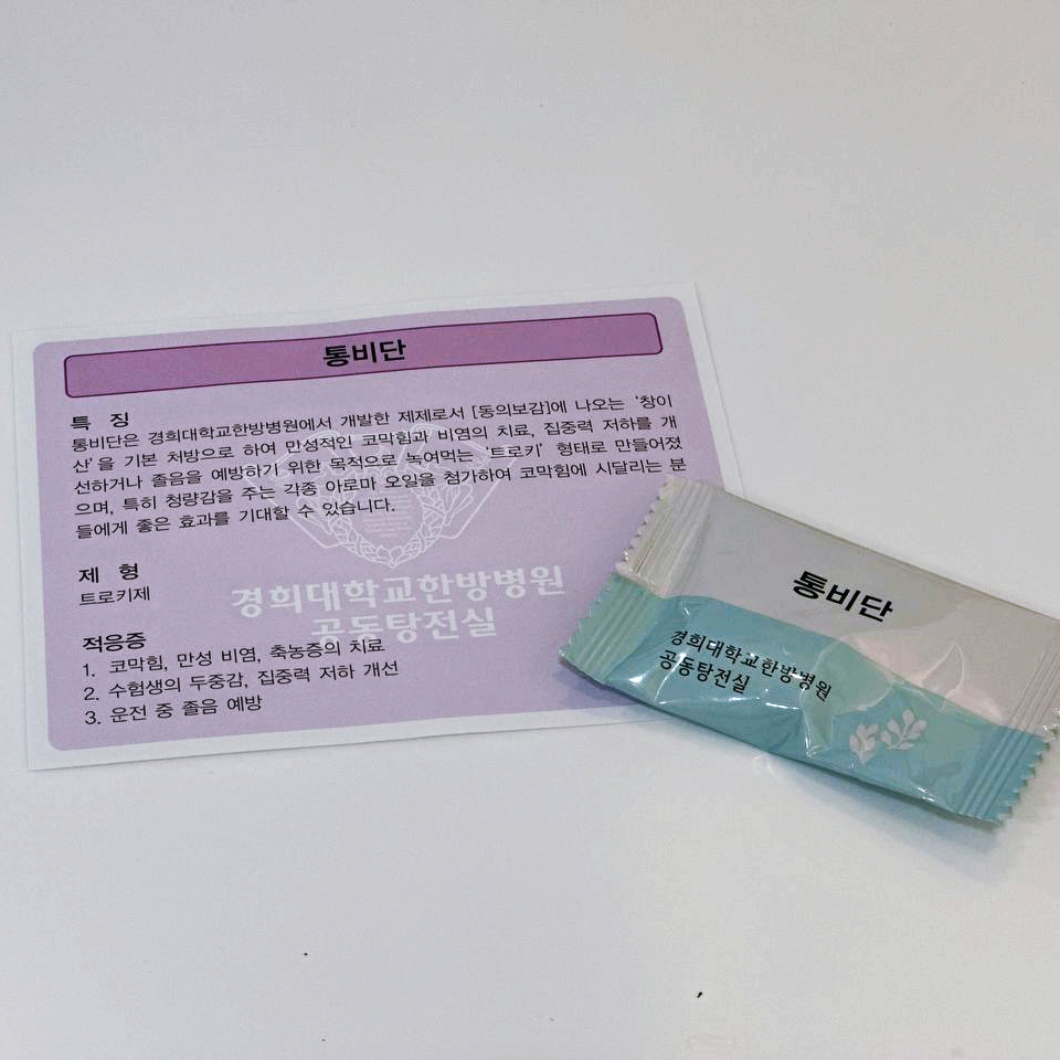 경희대학교한방병원 통비단 제품 포장과 제품 정보가 적힌 카드가 함께 놓여 있다.