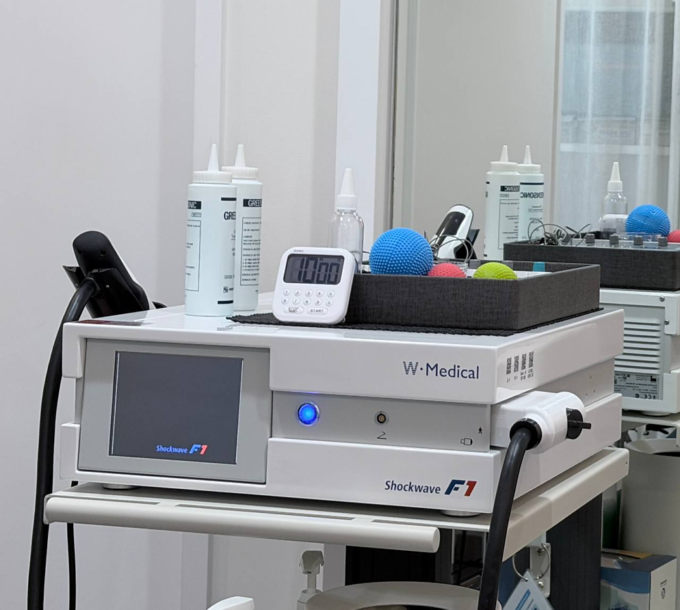 W. Medical Shockwave F1 체외충격파 치료기와 그 위에 놓인 젤, 타이머, 마사지볼