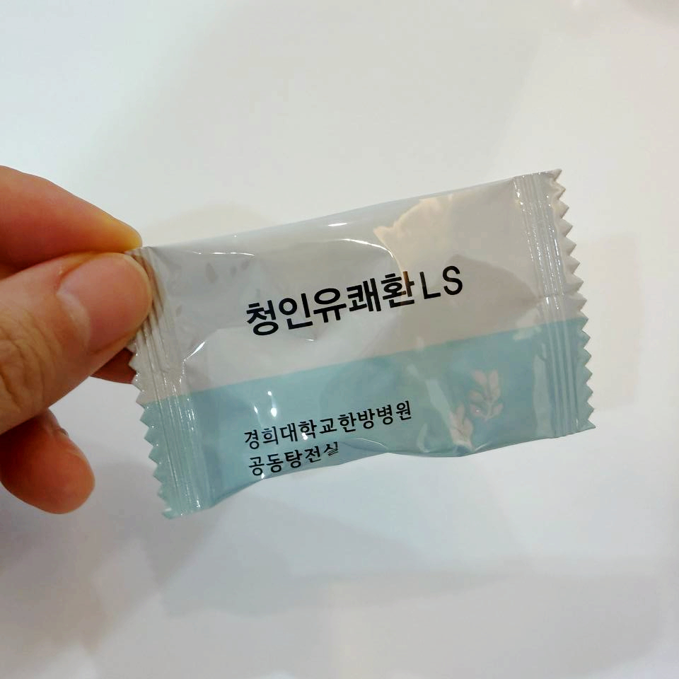 손이 '청인유쾌환 LS'와 '경희대학교한방병원 공동탕전실'이 적힌 은색 포장지를 들고 있는 모습
