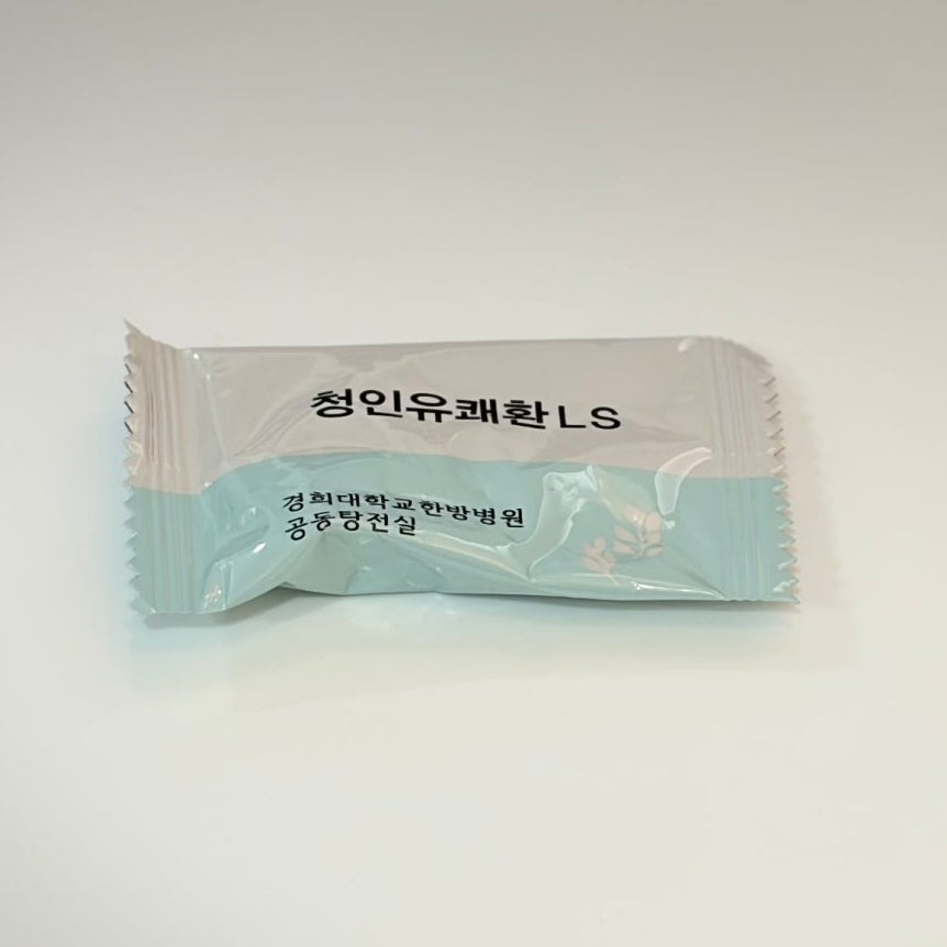 흰 배경에 '청인유쾌환 LS'라고 적힌 포장된 한약 제품이 놓여 있다. 포장지에는 '경희대학교 한방병원 공동탕전실' 문구도 보인다.
