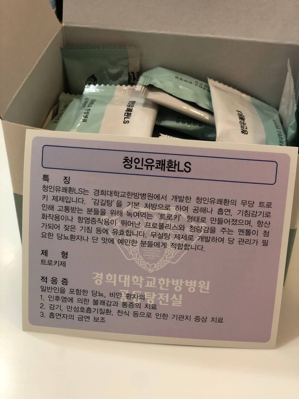 개봉된 상자에 개별 포장된 청인유쾌환LS 트로키가 담겨 있으며, 제품 정보가 적힌 안내문이 앞에 있습니다.