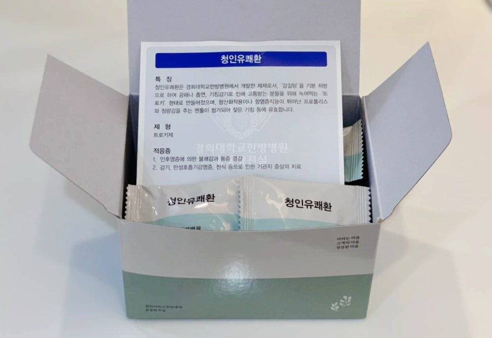 청인유쾌환 제품 상자가 열려 있고, 개별 포장된 환과 설명서가 들어있다.