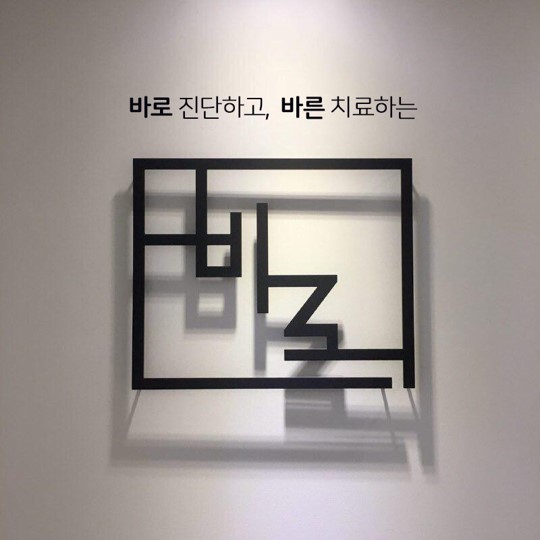 흰 벽에 '바로 진단하고, 바른 치료하는'이라는 검은색 글씨와 검은색 선으로 이루어진 사각형 모양의 장식물이 걸려 있다.