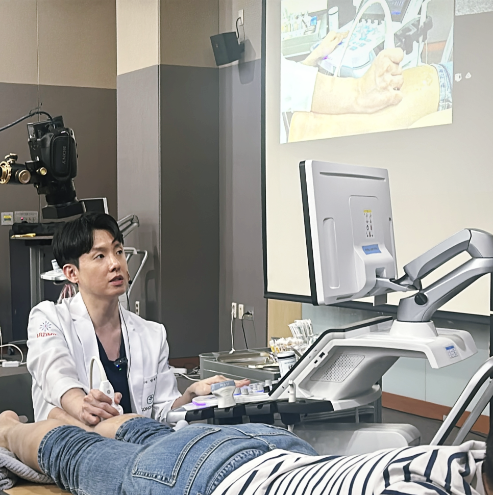 한의사가 환자의 다리에 초음파 기기를 대고 약침 시술을 시연하는 모습입니다.