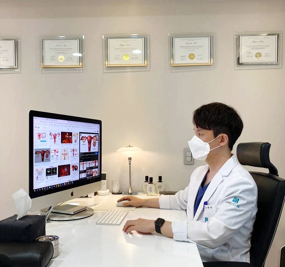 마스크를 쓴 의사가 컴퓨터 화면으로 여성 생식기 및 난소 낭종 이미지를 보고 있는 모습 — 초음파 약침·도침 임상 논문 | 서울 바로한의원