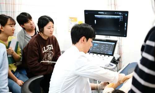 한의사가 초음파 화면을 보며 환자의 팔에 시술하고 여러 명이 이를 지켜보고 있는 모습