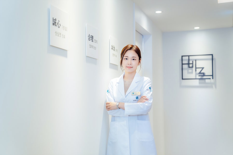 하얀 의사 가운을 입은 여성이 병원 복도에서 팔짱을 끼고 서서 카메라를 보고 있다 — 서울 바로한의원 초음파 약침·도침
