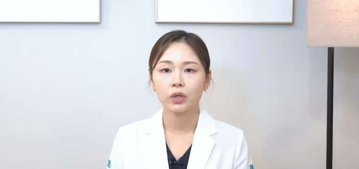 흰색 가운을 입은 여성이 정면을 바라보며 말하고 있다.