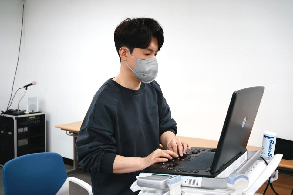 마스크를 쓴 사람이 학술대회에서 초음파 기기를 조작하는 모습.