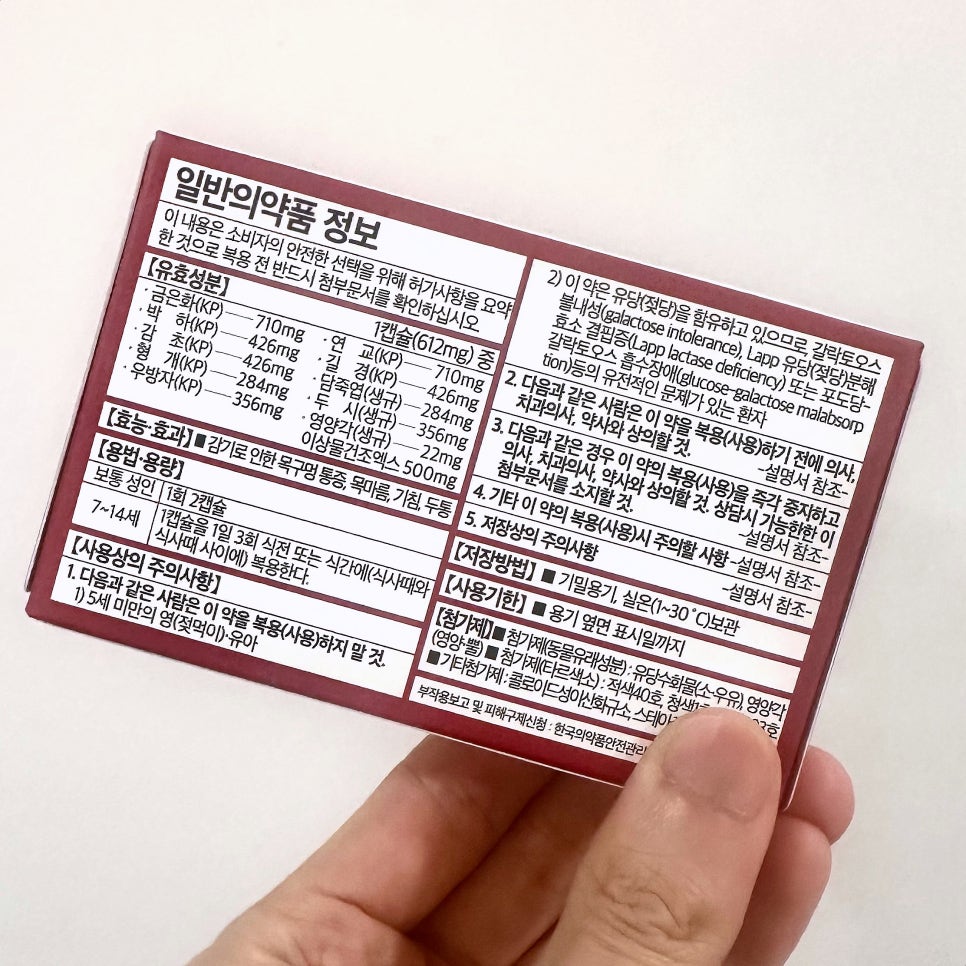 손이 일반의약품 정보가 적힌 갈색 약 상자를 들고 있다.