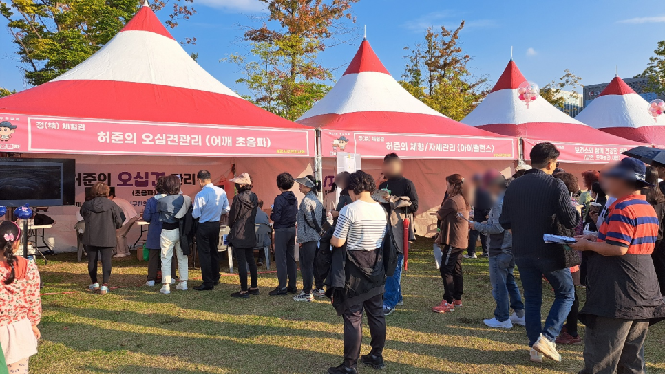 강서구 허준축제 야외 부스에서 사람들이 어깨 초음파 체험을 위해 모여 있다. 부스 내 화면에 초음파 영상이 표시되어 있다.