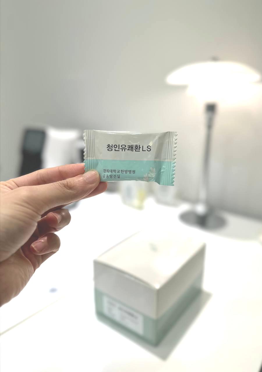 손이 '청인유쾌환 LS'라고 적힌 작은 포장지를 들고 있다.