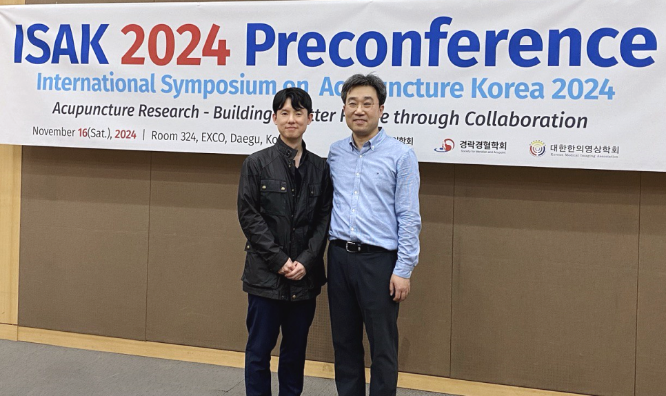 ISAK 2024 국제학술대회 배너 앞에서 두 남자가 서 있는 모습