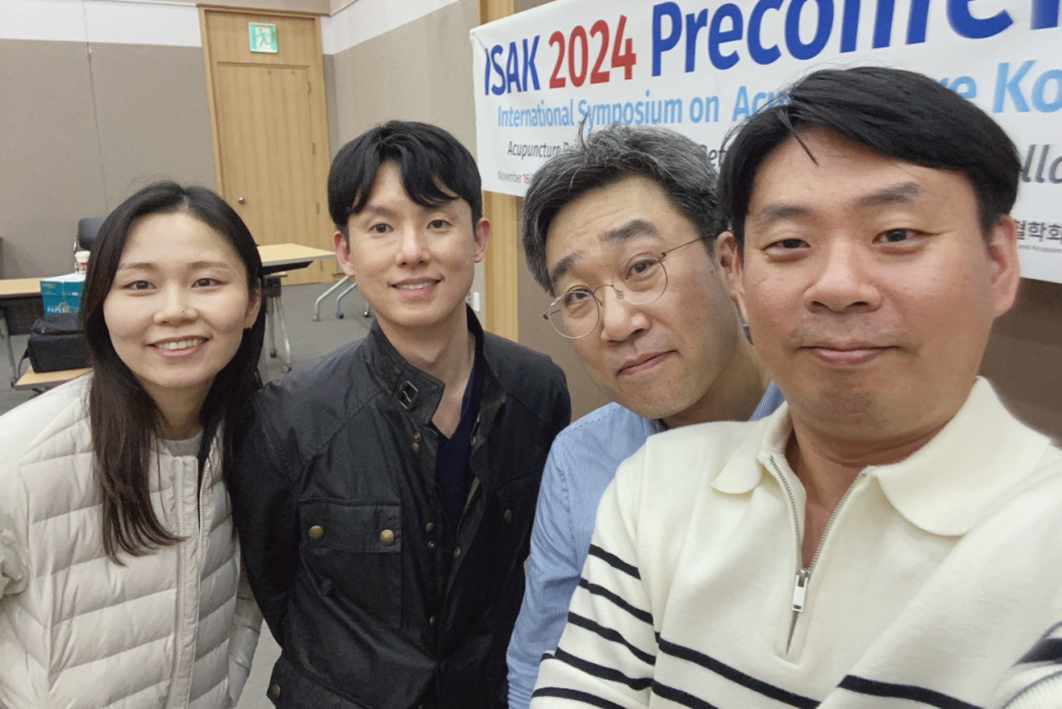 ISAK 2024 국제학술대회 현장에서 네 명의 사람들이 카메라를 보며 미소 짓고 있다.
