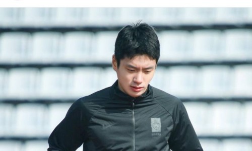 한국 대표팀 로고가 있는 검은색 운동복을 입고 아래를 응시하는 남성