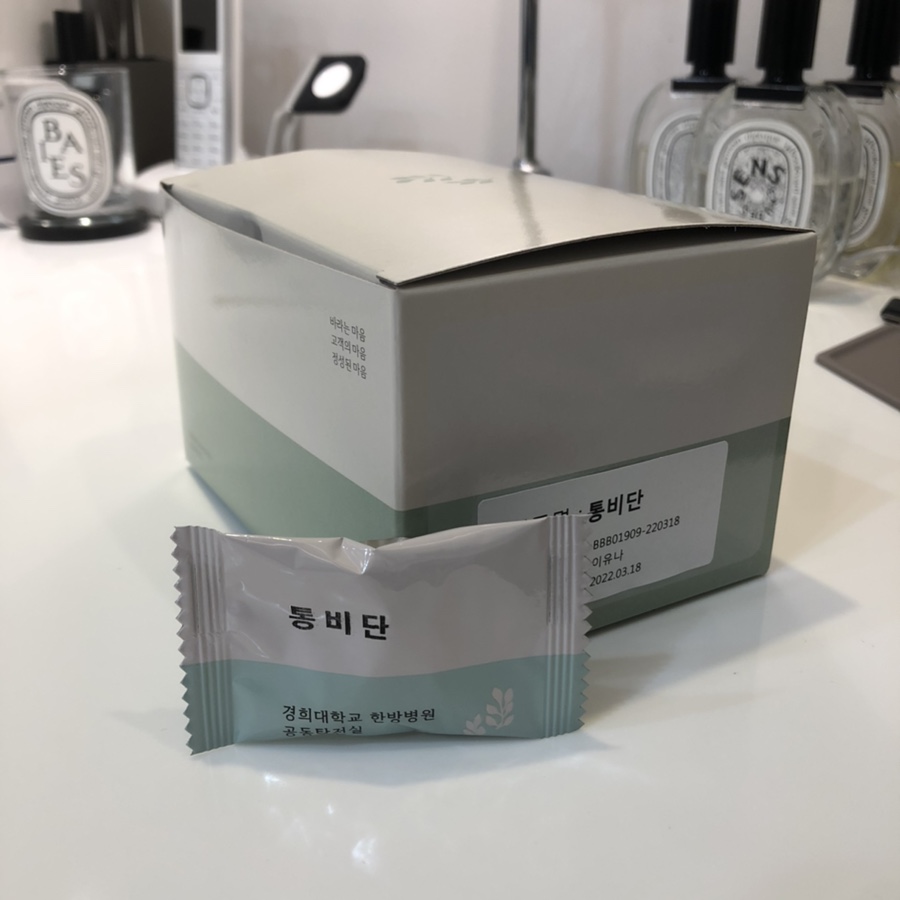 연두색과 흰색 상자 앞에 '통비단'이라고 쓰인 개별 포장된 한약이 놓여 있다.