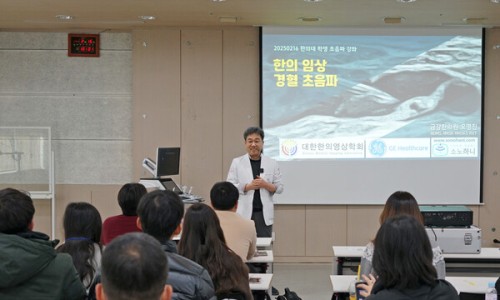 강사가 청중 앞에서 '한의 임상 경혈 초음파' 제목의 슬라이드를 띄운 채 강연하는 모습