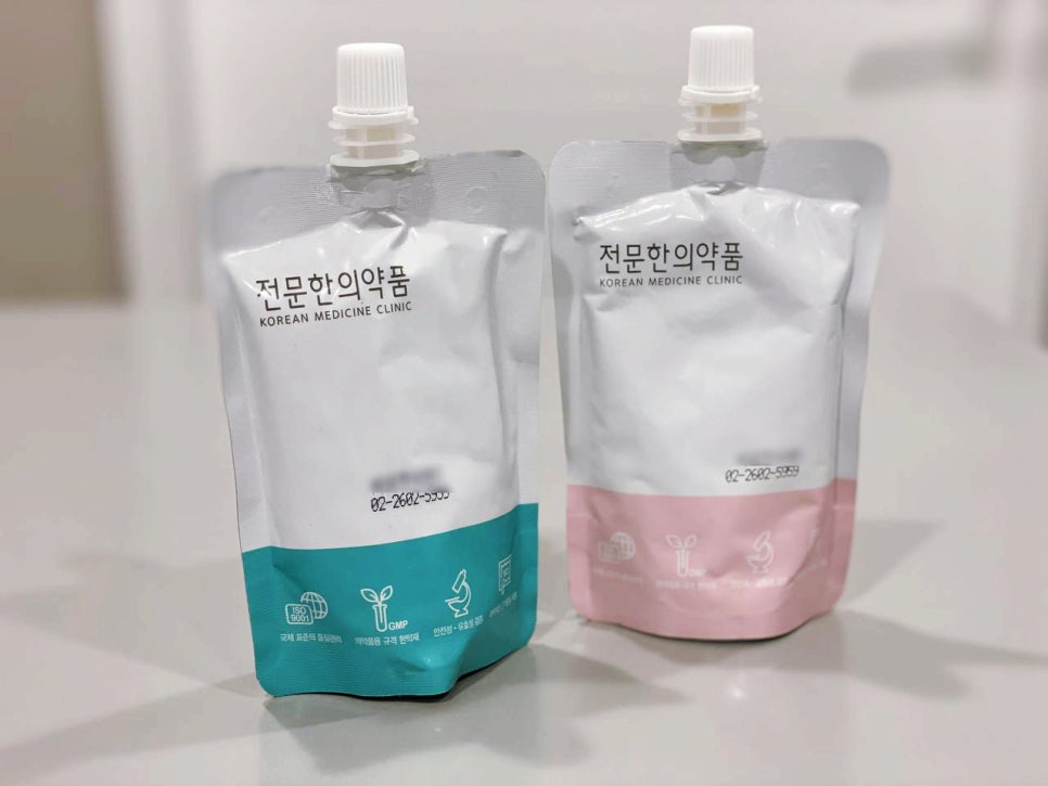 스크류 캡이 달린 흰색 파우치 두 개가 나란히 놓여 있습니다. 한 파우치는 하단이 청록색이고 다른 파우치는 하단이 분홍색입니다.