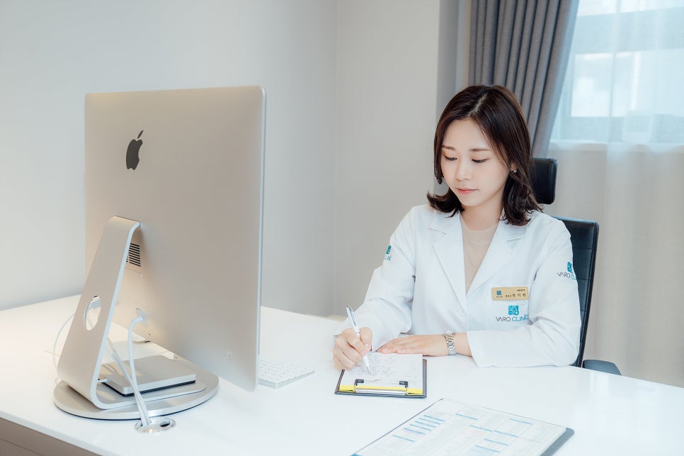 흰색 가운을 입은 여성이 책상에 앉아 서류에 내용을 작성하고 있다 — 서울 바로한의원 초음파 약침·도침