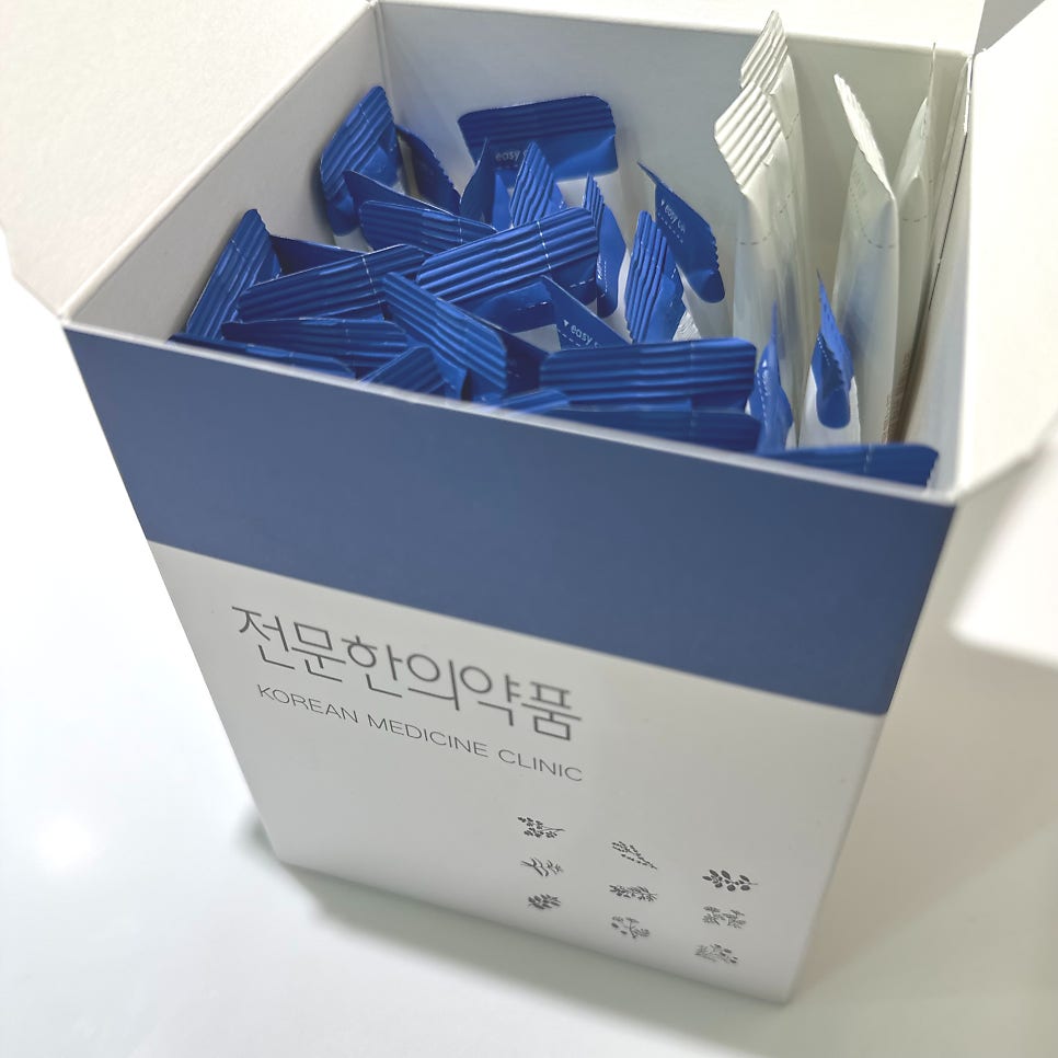파란색 띠가 있는 흰색 상자에 개별 포장된 파란색과 흰색 약봉투들이 담겨 있습니다.