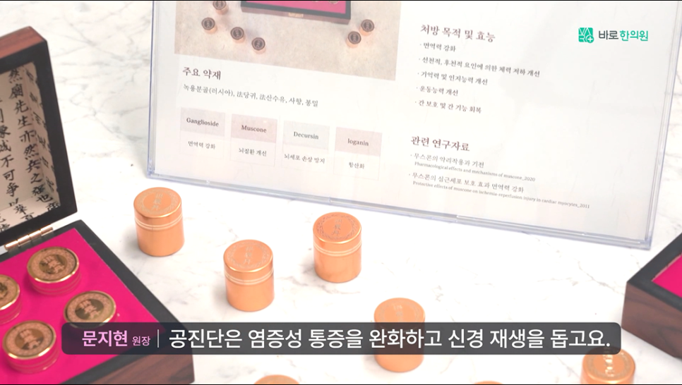 공진단 약재와 효능을 설명하는 안내판과 금색 용기들이 놓여 있고, 공진단 효능에 대한 자막이 있는 사진