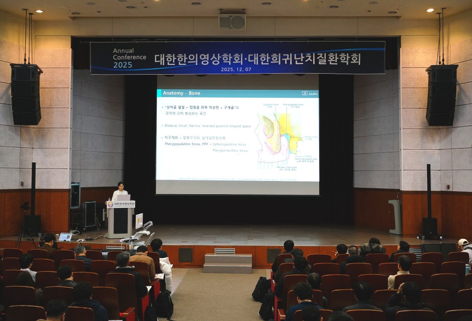 한의영상학회 학술대회에서 연자가 무대 위에서 발표하고 있으며, 스크린에는 뼈 해부학 관련 슬라이드가 보인다.