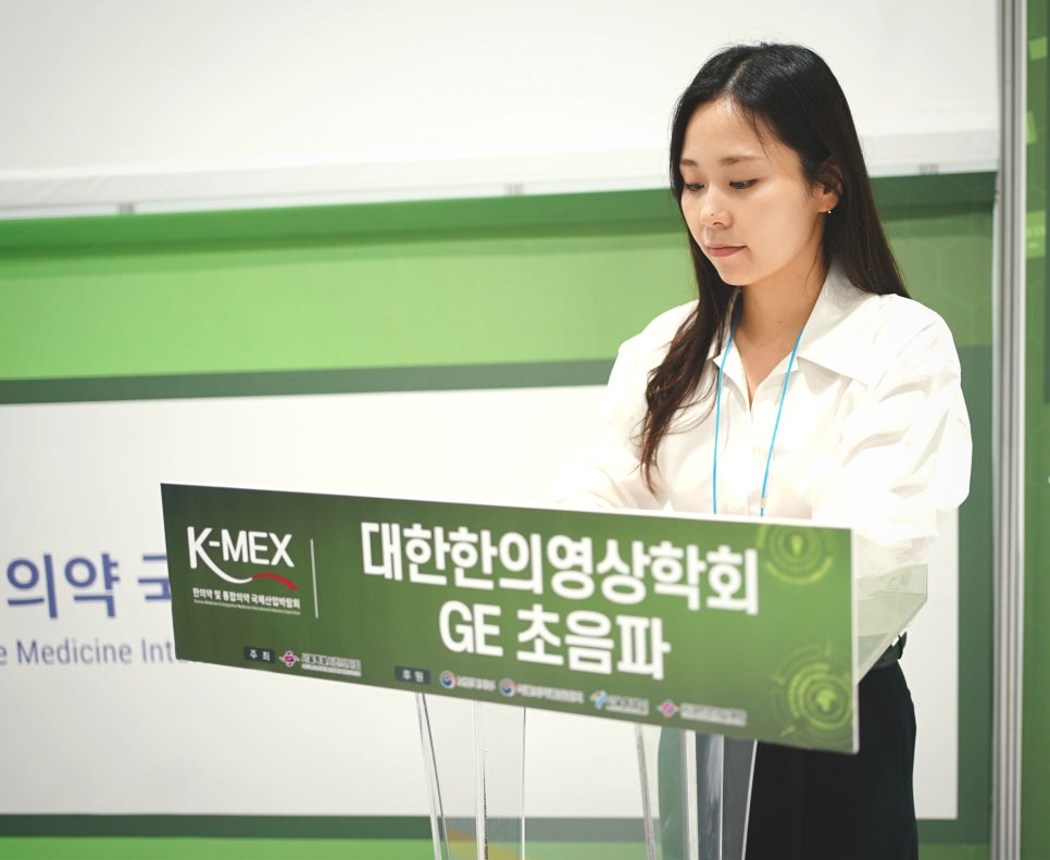 한의영상학회 GE 초음파라고 적힌 연단 뒤에 서 있는 여성