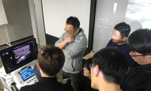 여러 명이 초음파 기기 화면에 보이는 초음파 영상을 함께 보고 있다.