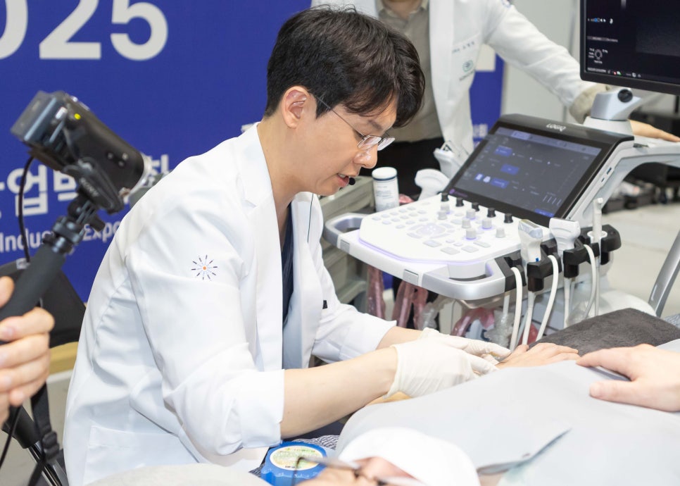 흰 가운을 입은 한의사가 초음파 기기를 사용하여 환자의 팔에 시술하는 모습
