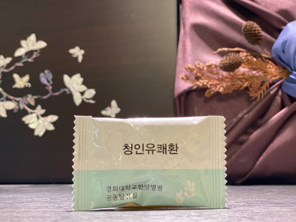 경희대학교한방병원 공동탕전실에서 제조된 청인유쾌환 한 포가 어두운 배경에 놓여 있다.