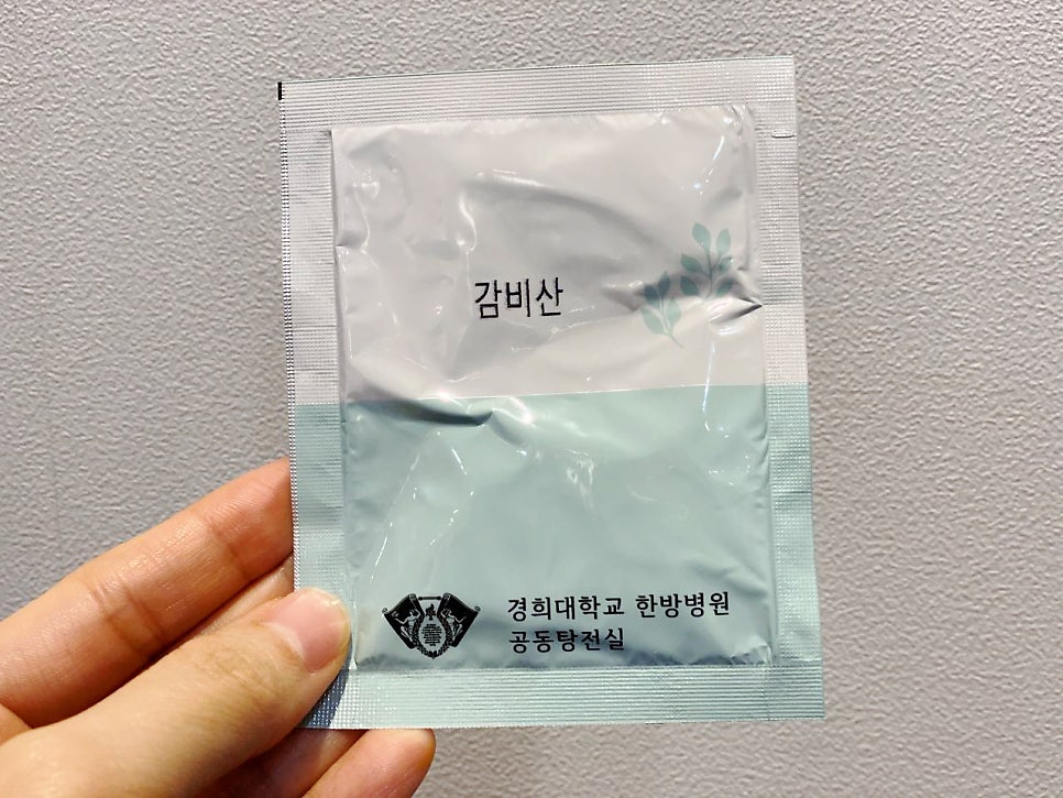 손이 경희대학교 한방병원 감비산 약 포를 들고 있는 모습