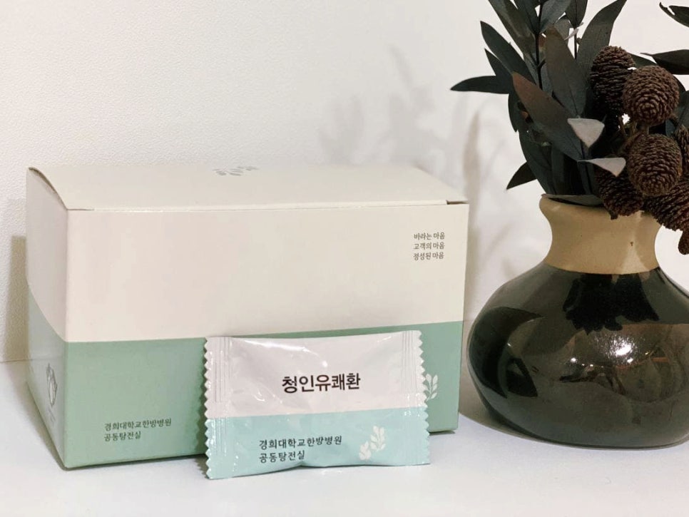 청인유쾌환 제품 상자와 파우치, 그리고 장식용 화병이 함께 놓여 있는 모습.