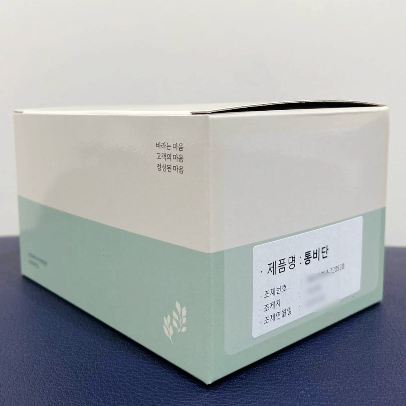 제품명 : 통비단이라고 적힌 연한 색상의 상자가 놓여 있다.