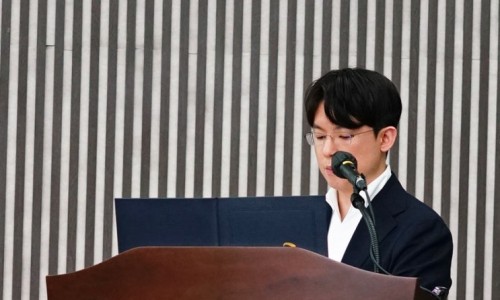 강단에서 마이크를 잡고 연설하는 남성