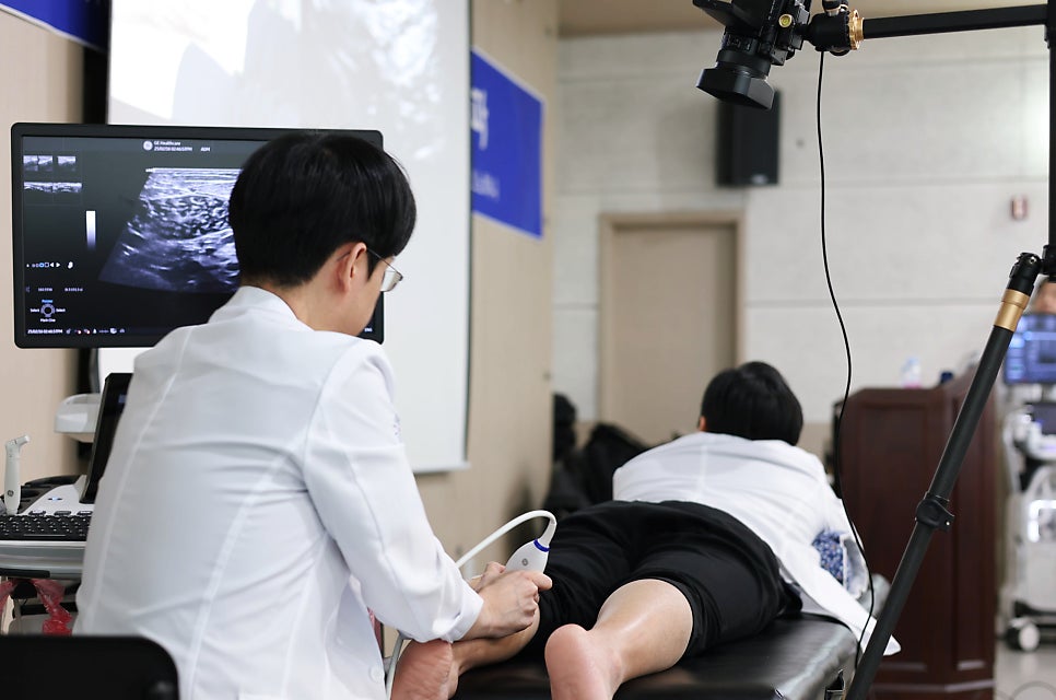 한의사가 환자의 다리에 초음파 기기를 대고 초음파 화면을 보고 있다.