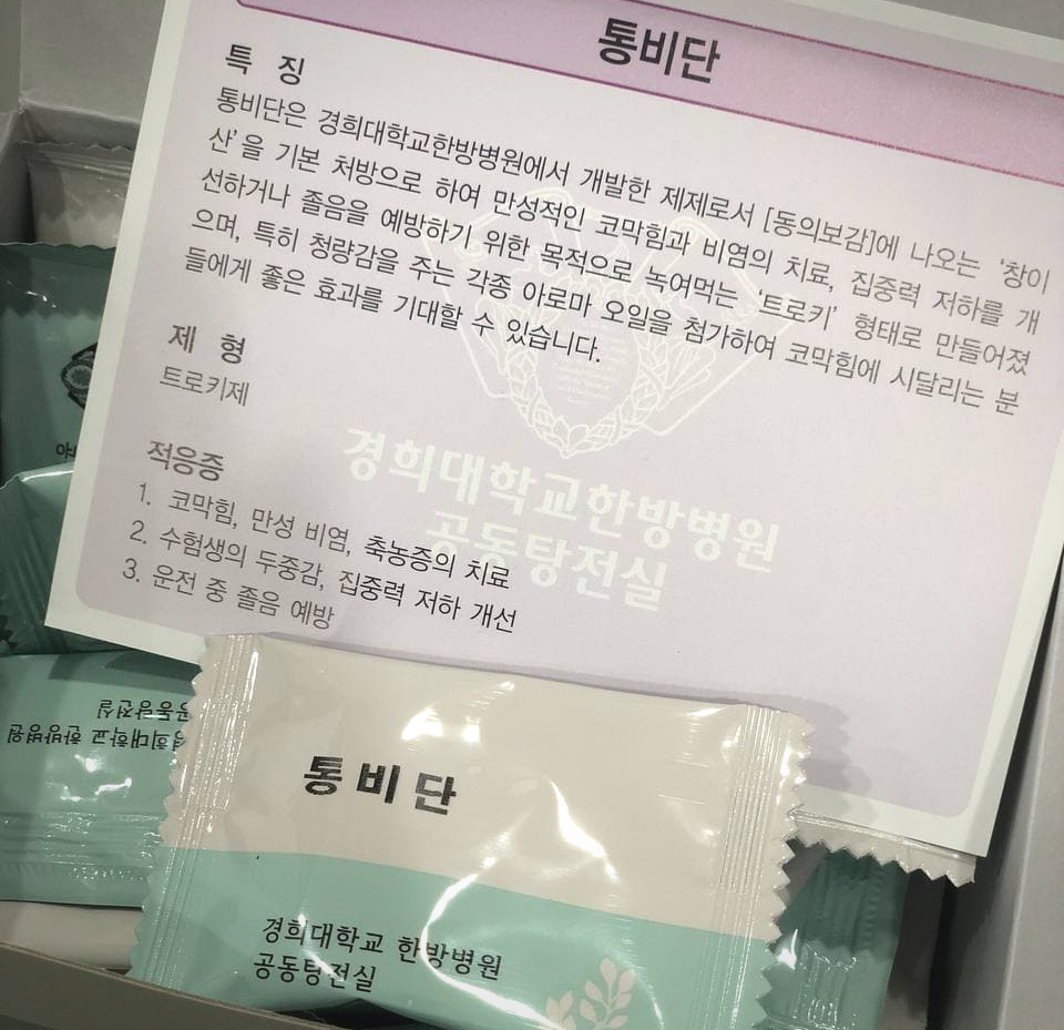 경희대학교 한방병원에서 개발한 통비단 제품 포장과 효능 및 적응증이 적힌 안내문이 함께 놓여 있는 모습