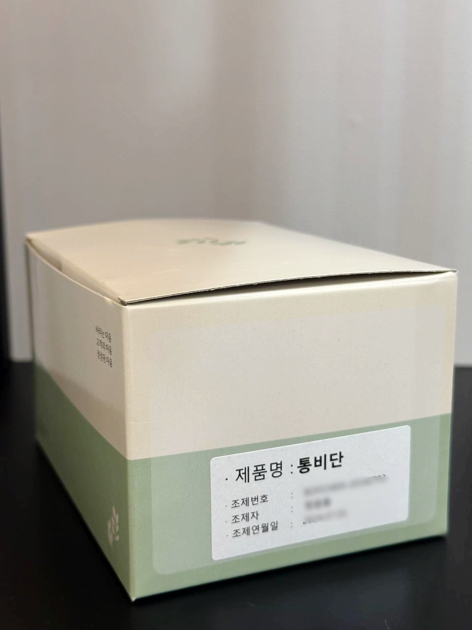 제품명 '통비단'이 적힌 라벨이 붙어 있는 연두색과 베이지색 상자.