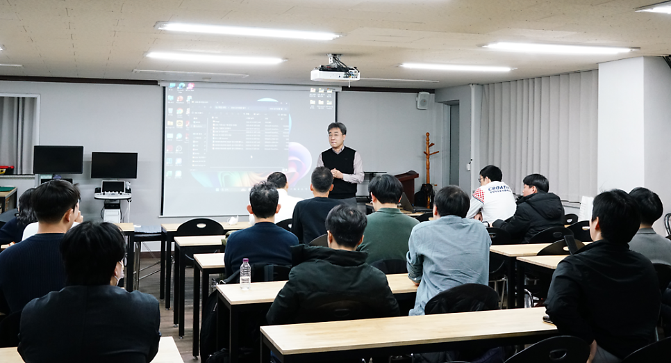 강사가 스크린 앞에서 수강생들에게 강의하고 있으며, 왼쪽에 초음파 기기가 보인다.