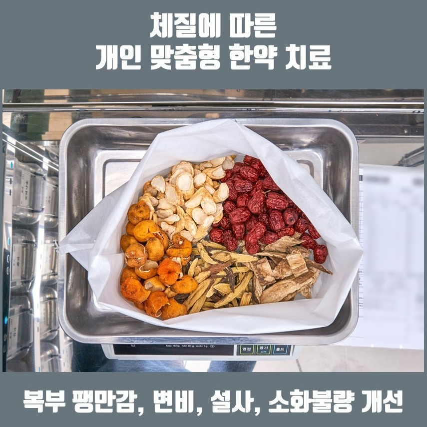 저울 위에 인삼, 대추 등 여러 종류의 마른 한약재가 담긴 흰 봉투가 놓여 있다.