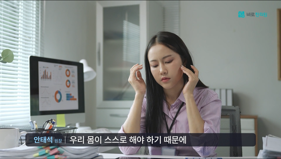 사무실 책상에 앉아 머리를 감싸 쥐고 있는 여성