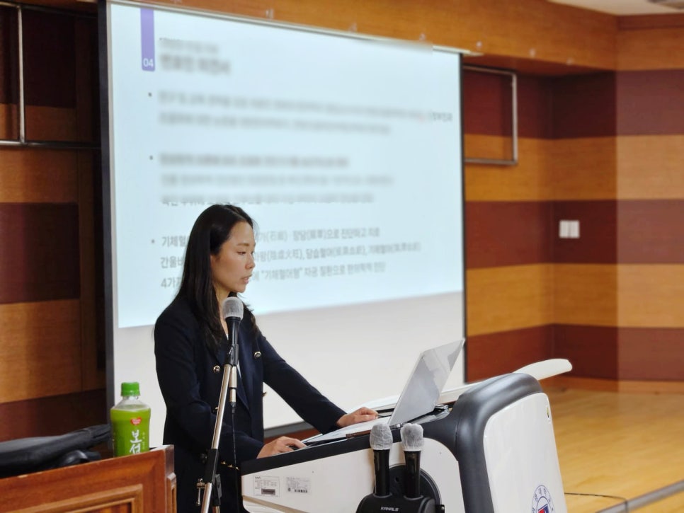 한의과대학 초청 강연에서 강사가 마이크 앞에서 노트북을 보며 발표하는 모습